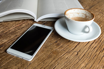 Killing time by reading a good book and a cup of coffee (empty on a wooden table)