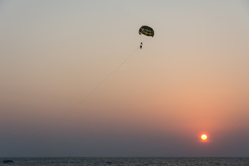 Silhouette of tourist playing parasailing during sunset