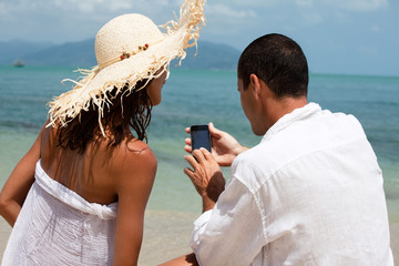 couple regardant un téléphone portable sur une plage au bord de la mer