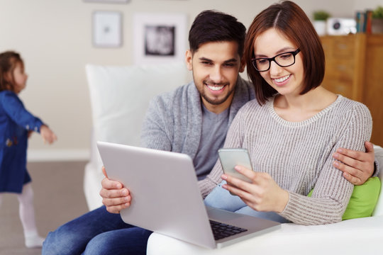 paar sitzt in der wohnung mit laptop und handy