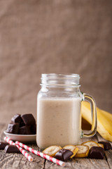 Banana smoothie  with chocolate in glass jar with drinking straw