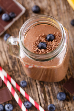 Chocolate smoothie in glass jar with blueberries and drinking st