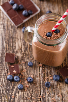 Chocolate smoothie in glass jar with blueberries and drinking st
