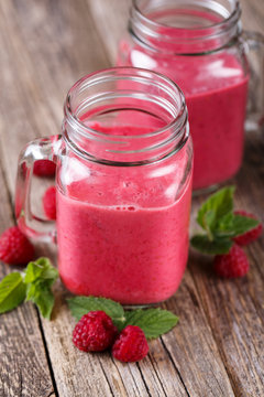 Tasty raspberry smoothie on wooden table.