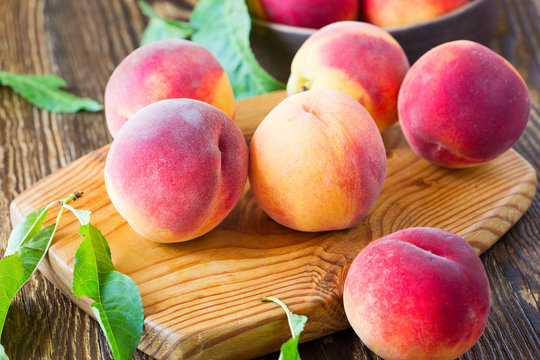 Ripe organic peaches in ceramic bowl on wooden table