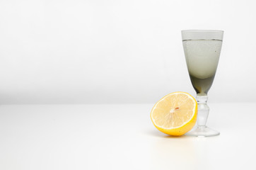 A glass of vodka with lemon on a light background