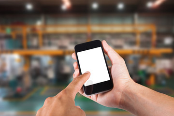Person using smartphone white screen holder on hand with blurry background of industrial factory.