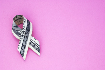 Hundred dollar breast cancer ribbon on a textured pink background.