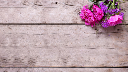 Spring pink peonies flowers on aged wooden background.