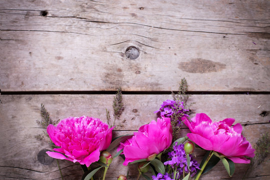 Border from  pink peonies flowers on aged wooden background