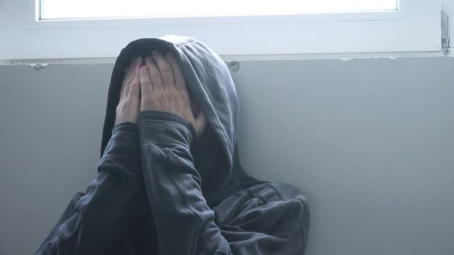 Drug addiction concept, narcotic addict in crisis situation with hands covering face