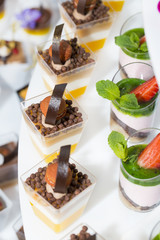 mini canapes in plastic cups decorated with edible flowers