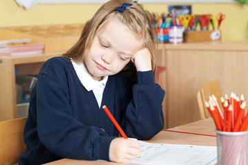 Naklejka na ściany i meble Bored Female Elementary School Pupil At Desk