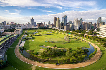 green stadium field of horserunner in center on bangkok cityscap
