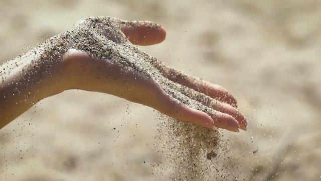 The macro snapshot of hand with sand strewed to fingers.