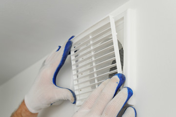 Worker installs ventilation grille. - obrazy, fototapety, plakaty