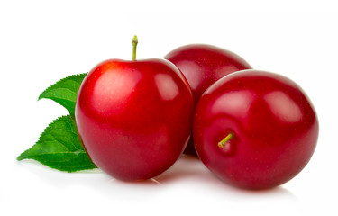 Red plum fruits with green leaves isolated
