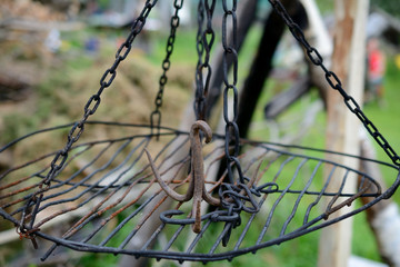 Rusty iron triple hook on grate hanging on chains