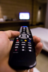 Hand holding black remote television with blurry background