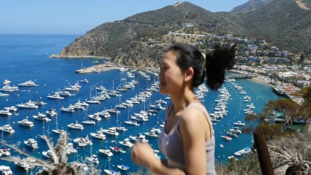 Attractive Asian woman jogging. The bay and town of Avalon on Catalina Island are in the background.