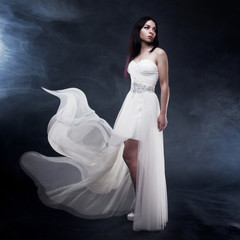 Fototapeta premium Beautiful sexy young woman. Portrait of girl in long white dress, mystical, mysterious style, dark background