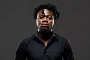 Obraz premium Young successful african businessman posing over dark background.