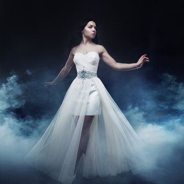Beautiful sexy young woman. Portrait of girl in long white dress, mystical, mysterious style, dark background