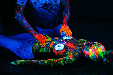 Concept. DJ playing at the club. Girl painted in UV powder as a
