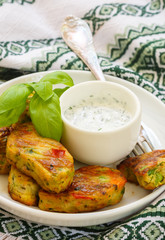 Healthy vegetarian potato patties with carrots, broccoli, bell pepper, green peas and onions with sour cream sauce with dill and Basil. Selective focus
