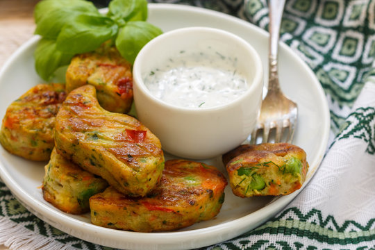 Healthy vegetarian potato patties with carrots, broccoli, bell pepper, green peas and onions with sour cream sauce with dill and Basil. Selective focus
