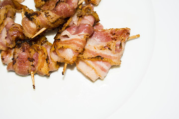 Rolls of slices of cooked bacon subject with a toothpick
