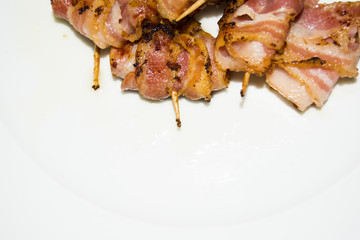 Rolls of slices of cooked bacon subject with a toothpick