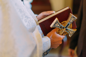 Beautiful golden cross in male hands of priest wearing gold robe on ceremony at christian cathedral church, holy sacramental event.