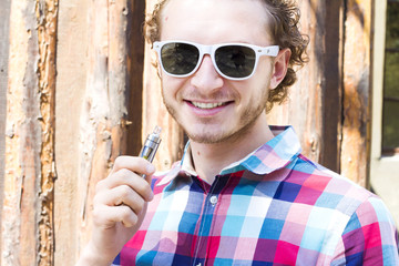 Happy young vaper. Stylish hipster vaping outdoor. Electronic cigarette.