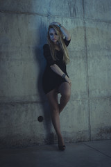 Fototapeta premium blonde dressed in skintight black costume on a gray cement wall