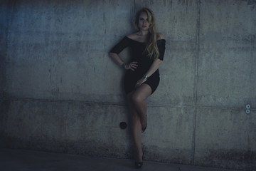 Fototapeta premium blonde dressed in skintight black costume on a gray cement wall