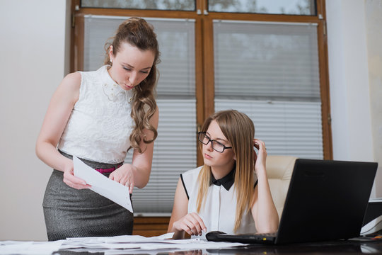 Two women business partners look on financial statements, statistics and documents