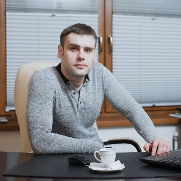 office worker freelancer sits at the desk and working on laptop during coffee break at the office