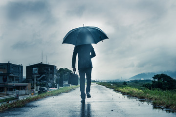 傘を差して歩くビジネスマン,暗いイメージ