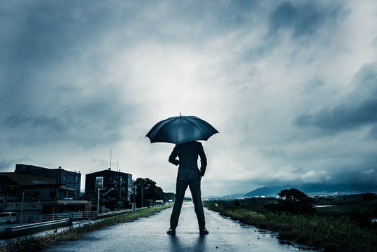 傘を差して歩くビジネスマン,暗いイメージ