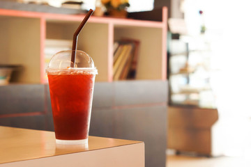 A glass of takeaway iced tea with cafe background