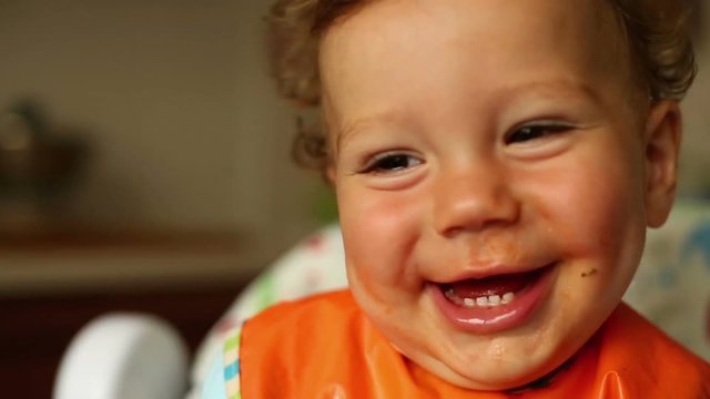Baby is eating spaghetti and laughing

