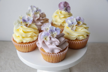 Purple and yellow cupcakes with sugared edible flowers on cake s
