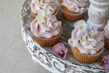 Purple cupcakes with sugared edible flowers on vintage cake stand