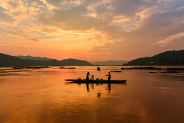 Fototapeta premium The suluate fisherman casting a net into the water during on sunset,Nongkhai Thailand