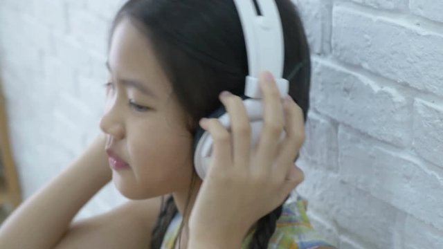 4K : Attractive Asian girl listening music by headphone in the room