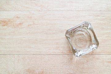 Clean empty glass ashtray on a wooden background.