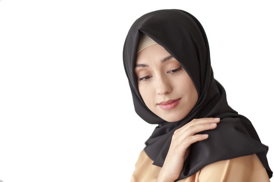 Studio portrait of a young woman in traditional Muslim dress and black scarf on her head, isolated on white background