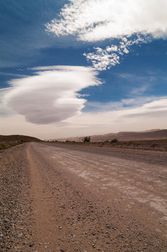 Unpaved road and lenticular clouds in the Mojave desert in California. © angeldibilio