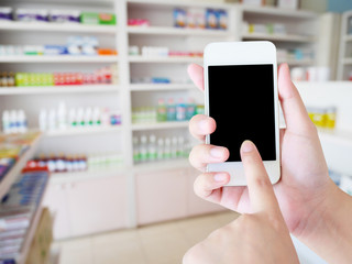 Fototapeta na wymiar women using smartphone in the pharmacy blurred background